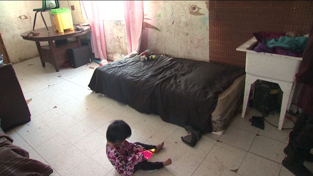 A child plays on the floor of a room in Garden Hill.