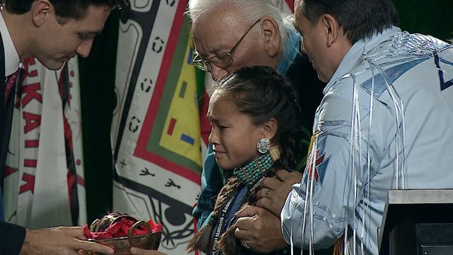 Autumn Peltier, 12, hands water bundle to Prime Minister Justin Trudeau. Autumn is flanked by AFN National Chief Perry Bellegarde and AFN Elder Elmer Courchene