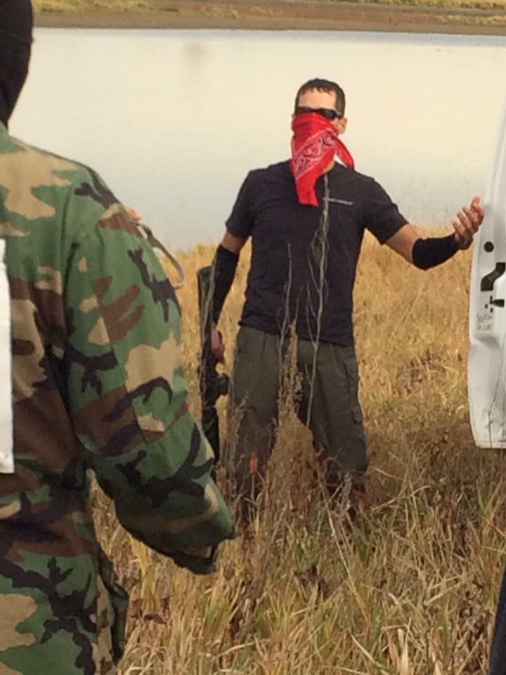 Kyle Thompson, with red kerchief over his face, holding an assault rifle during confrontation with water protectors on Oct. 27. Facebook photo